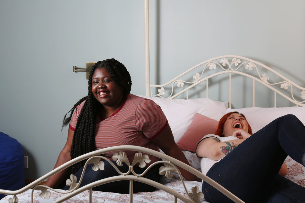 Young Plus Size Women Sitting On Bed Laughing