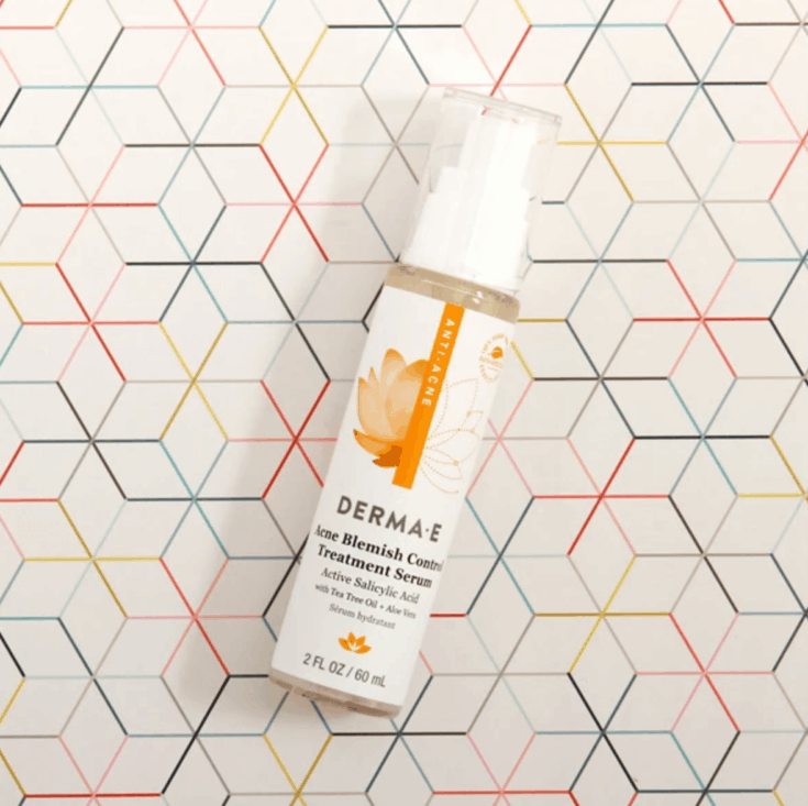bottle of DERMA E Anti-Acne Acne Blemish Control Treatment Serum on a multicolored background.