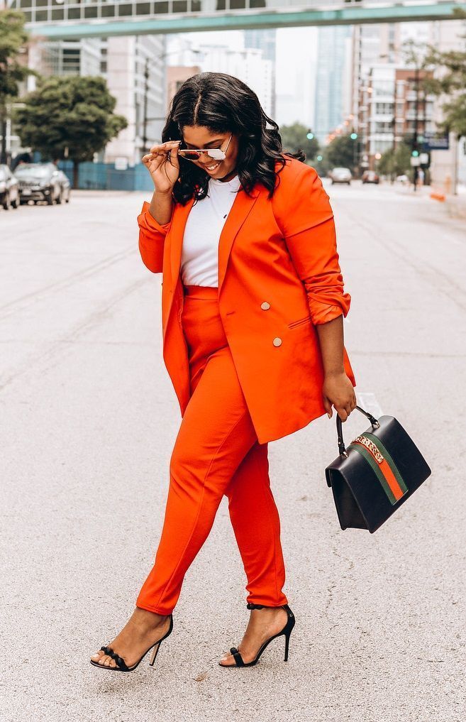 woman wearing a bright orange pantsuit with matching blazer posing in front of camera. with the street in the background.12 Timeless Classics That Will Never Go Out of Style