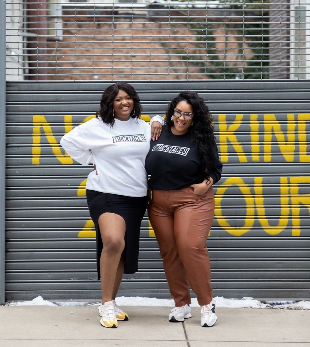 essie golden and Katie- Thick Laces Cofounders- pose in from of a garage, both wearing street wear and sneakers