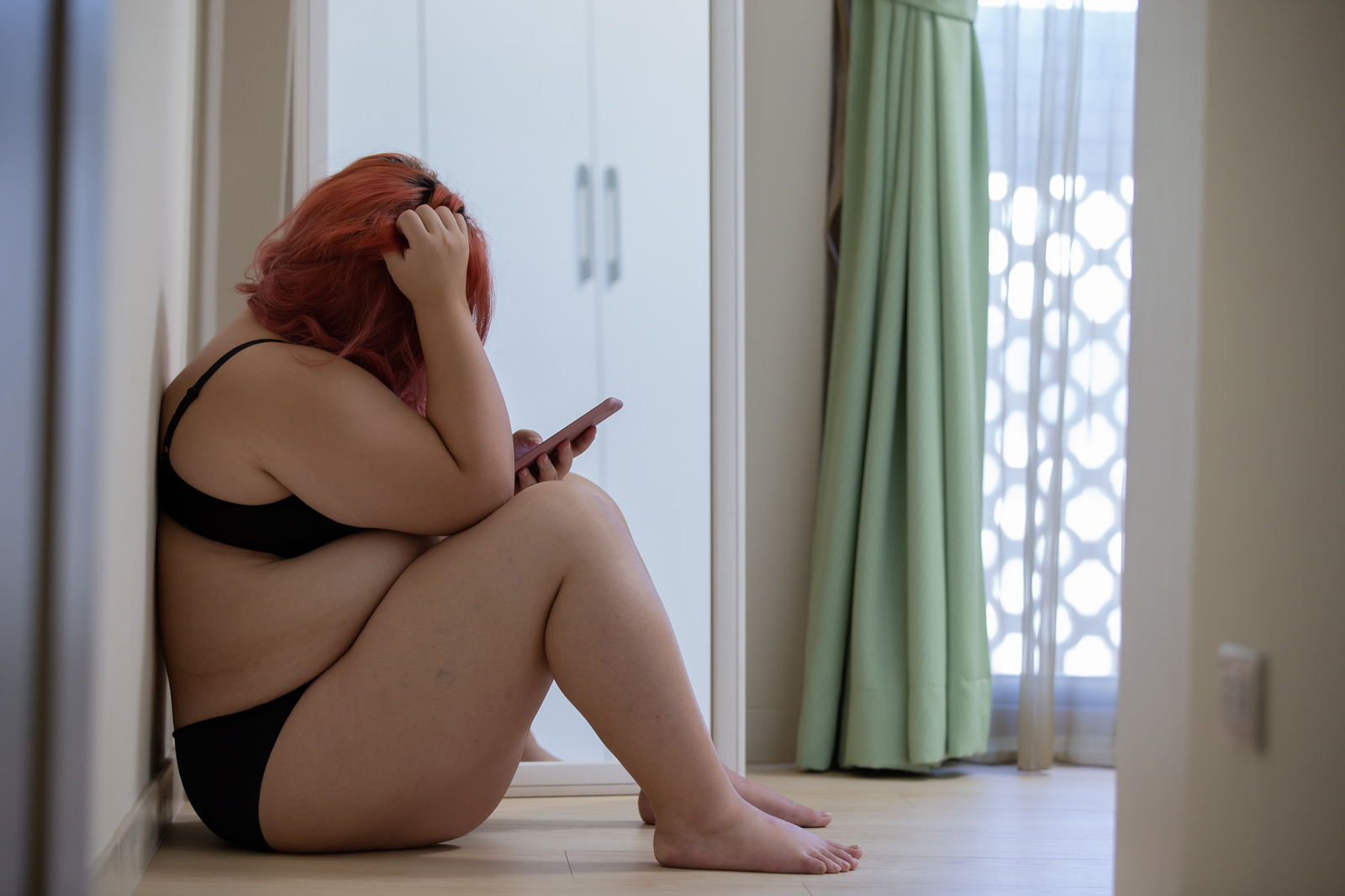 plus size woman looking at her phone in underwear STOCK PHOTO