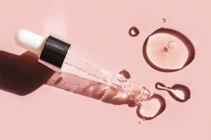 small dropper with clear liquid against pink background. skincare