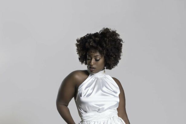 a Black person stands in an off-white satin jumpsuit with no sleeves.