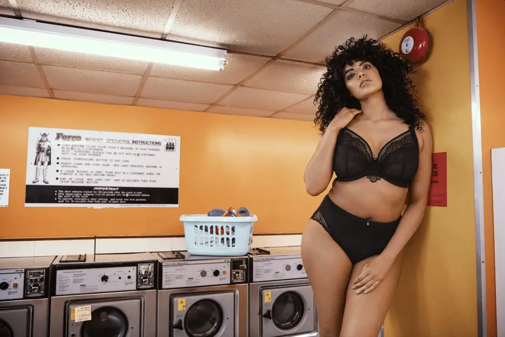 Here are 5 Full Figured Bra Brands to KNOW!
Image of a woman standing in a laundromat setting wearing the Priya plunge bra