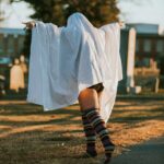 plus size woman with ghost costume, tights, and sneakers