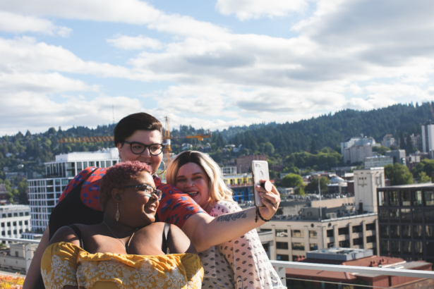 plus size black woman with short hair taking selfie with plus size woman with dark hair and plus size woman with blonde hair in front of a picturesque view