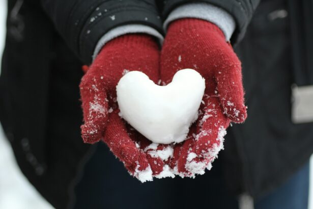 Hands wearing gloves holding a snowball in the shape of a heart