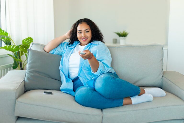 A cheerful woman watching romantic comedy movies with a plus-size leading lady