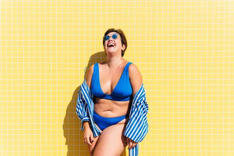 Beautiful and confident plus size woman having fun at the beach, posing on colorful wall background - concepts about body acceptance, body positive, self confidence and body care