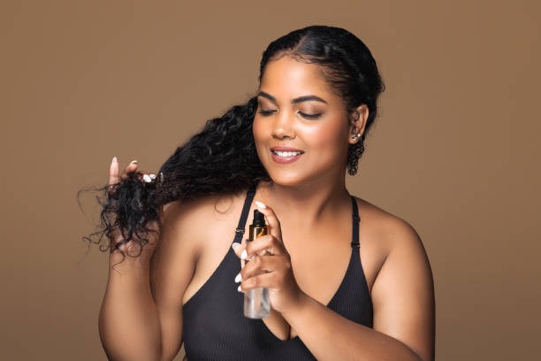 imgi 22 haircare concept beautiful latin plus size lady applying hair spray for curls using new