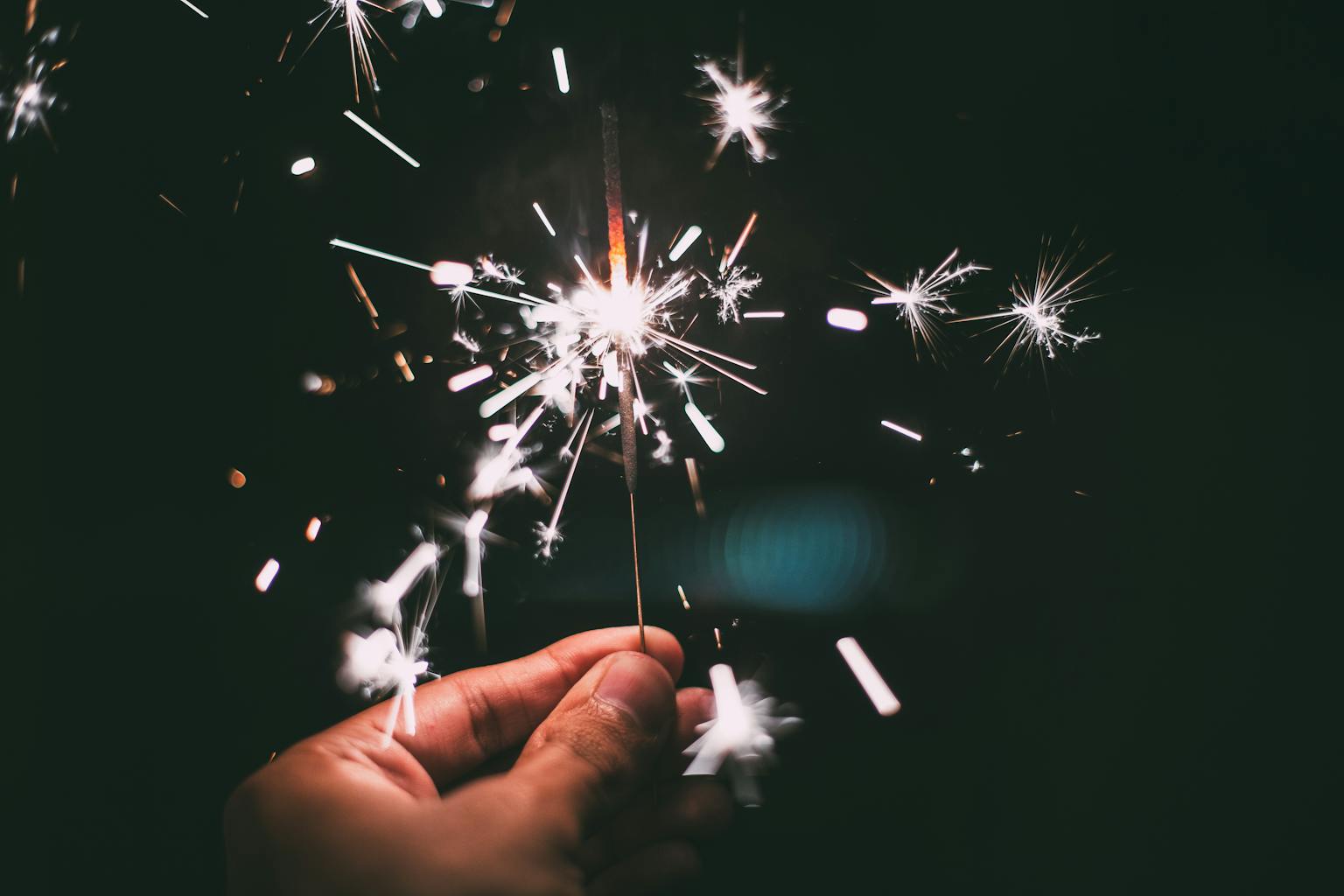 A hand holding a sparkler glowing brilliantly in the night, perfect for festive and holiday themes.