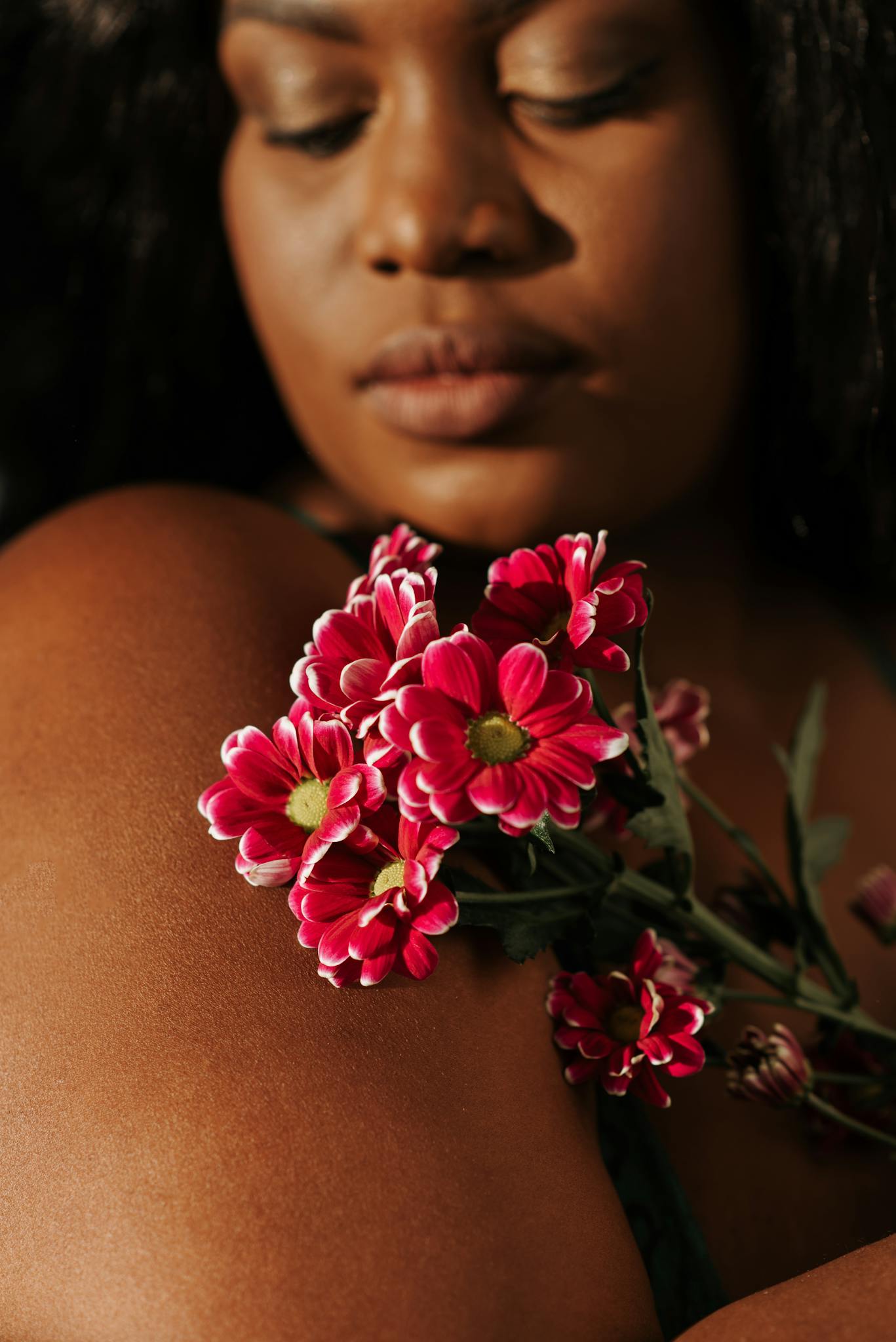 A peaceful portrait of a woman holding vivid geranium flowers, evoking calmness and beauty.