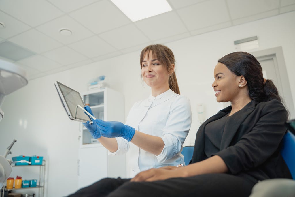 Dentist and patient discussing treatment plan using a tablet in a modern clinic setting.