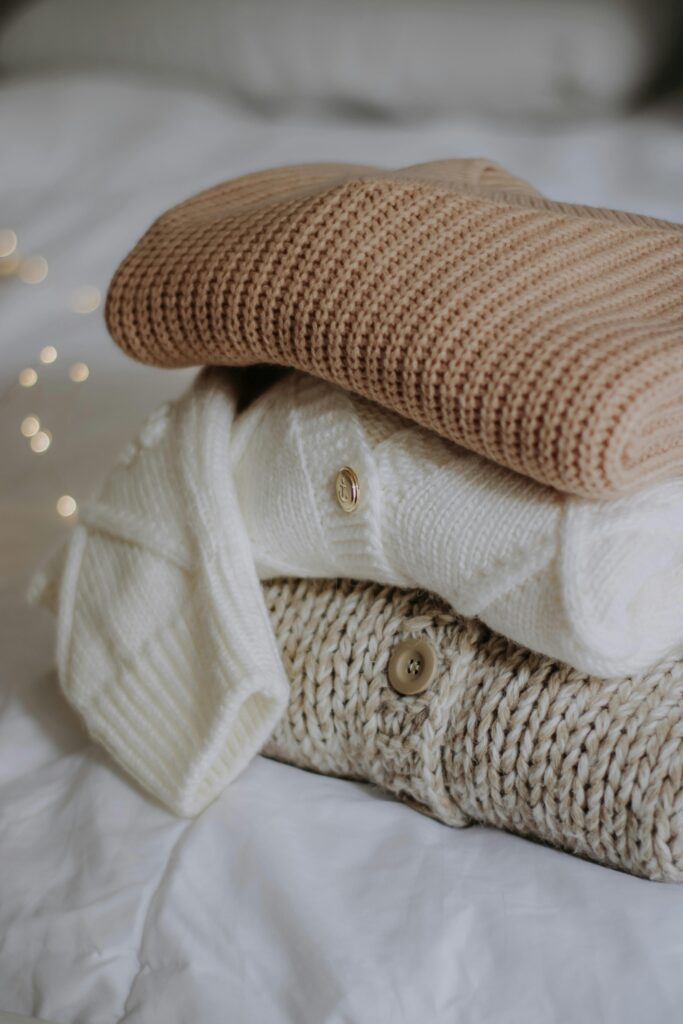 Sweaters Stacked on Bedclothes
