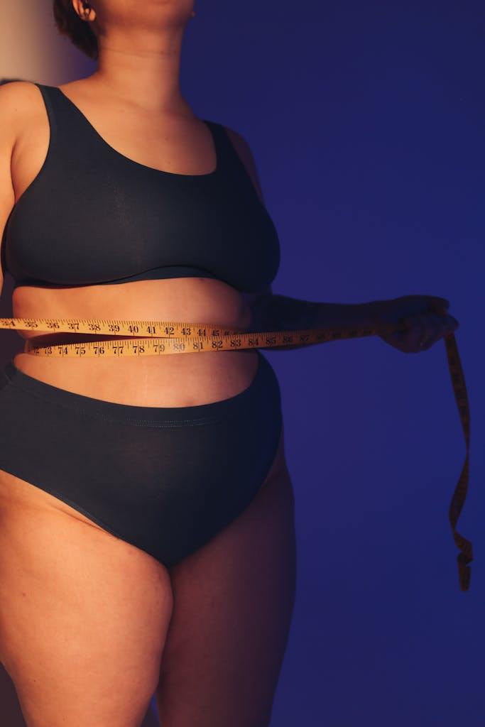 Plus-size woman measuring waist with tape measure instead of a scale.