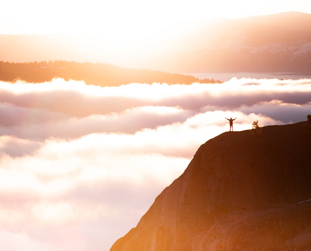 Silhouette of a person standing triumphant on a mountain cliff amidst the breathtaking morning clouds.

new year theme instead of resolutions