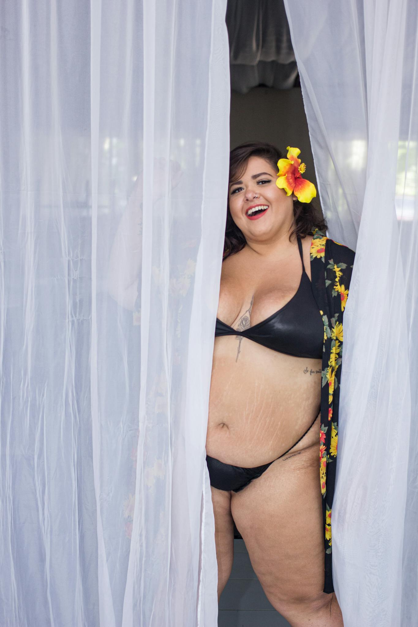 Smiling plus size woman in bikini with flower accessory enjoying summer in Brazil.