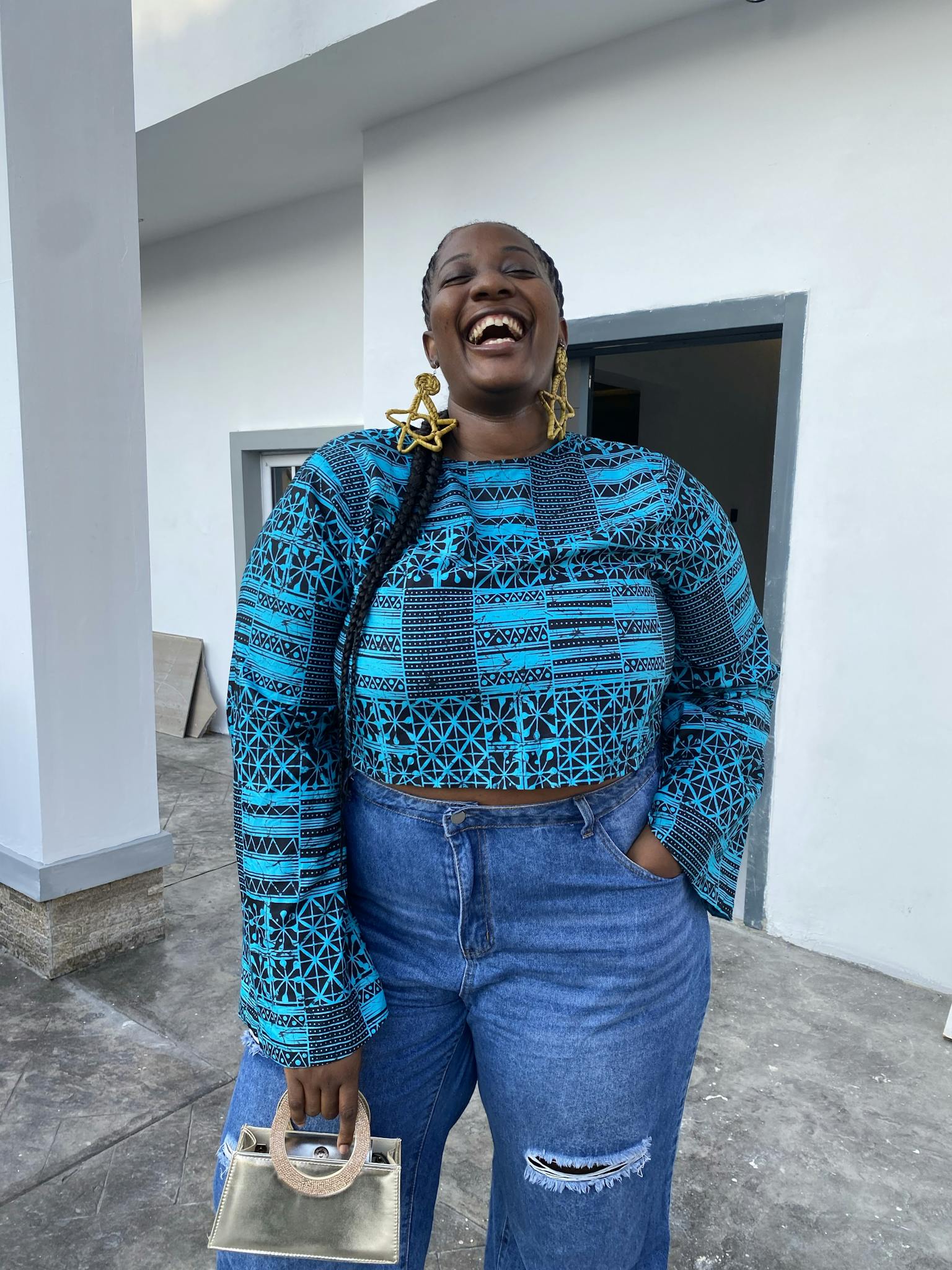 Smiling woman in ethnic blue attire and denim jeans exudes joy outdoors.