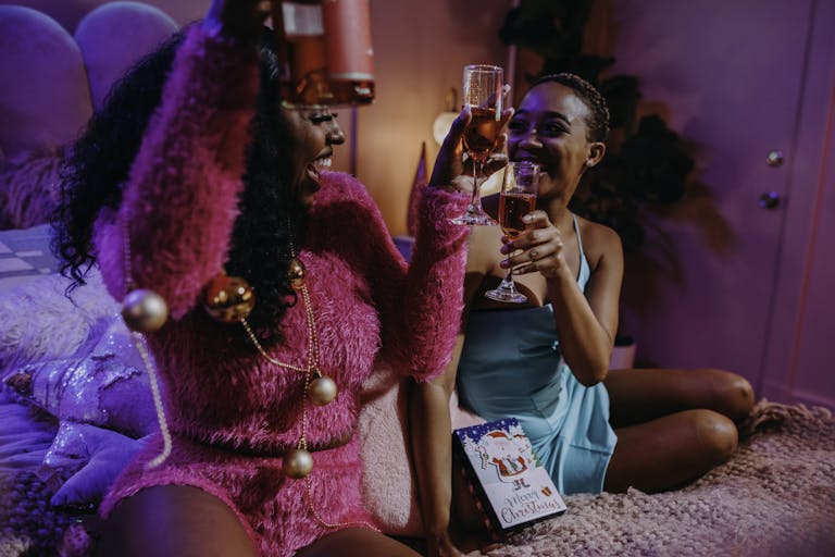 Two women celebrating indoors with drinks, embodying the festive holiday spirit and friendship. compliments plus size women want