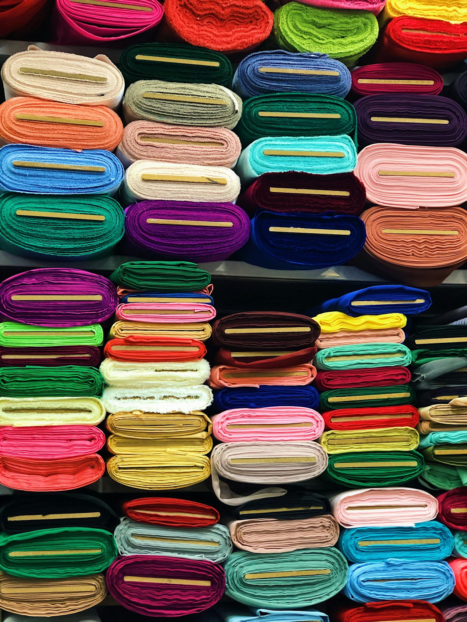 Vibrant stacked textiles create a vivid display on indoor store shelves.