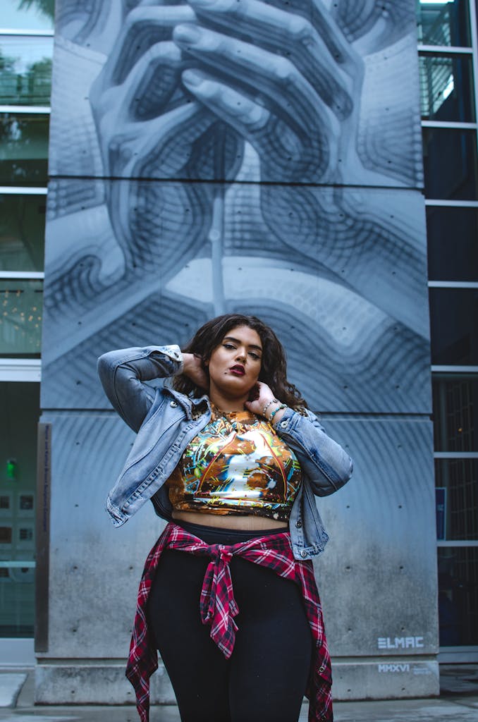 Young confident ethnic body positive female in casual clothes standing near wall with blue graffiti in city street and looking at camera in daytime
posture tips for plus size women