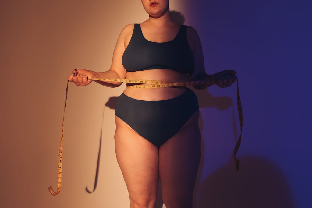 Confident plus size woman in studio holding a tape measure, emphasizing body positivity.
plus size style hacks