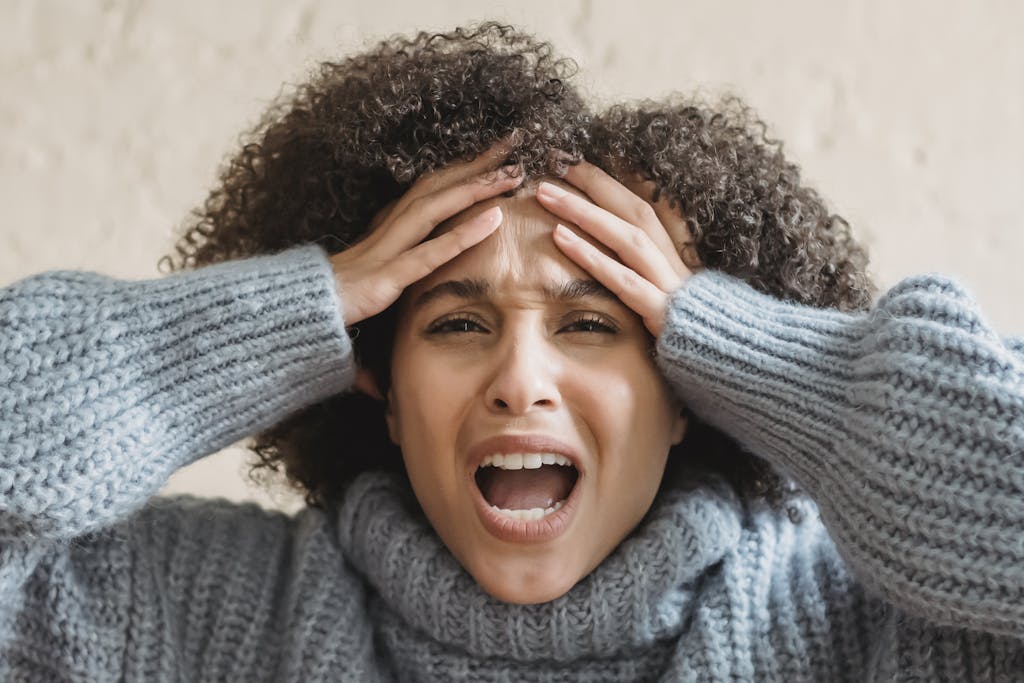 Expressive African American woman with curly brown hair touching head and yelling against light background
hidden costs of being plus size