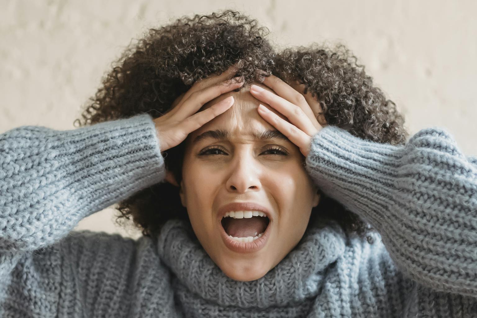 Expressive African American woman with curly brown hair touching head and yelling against light background
hidden costs of being plus size