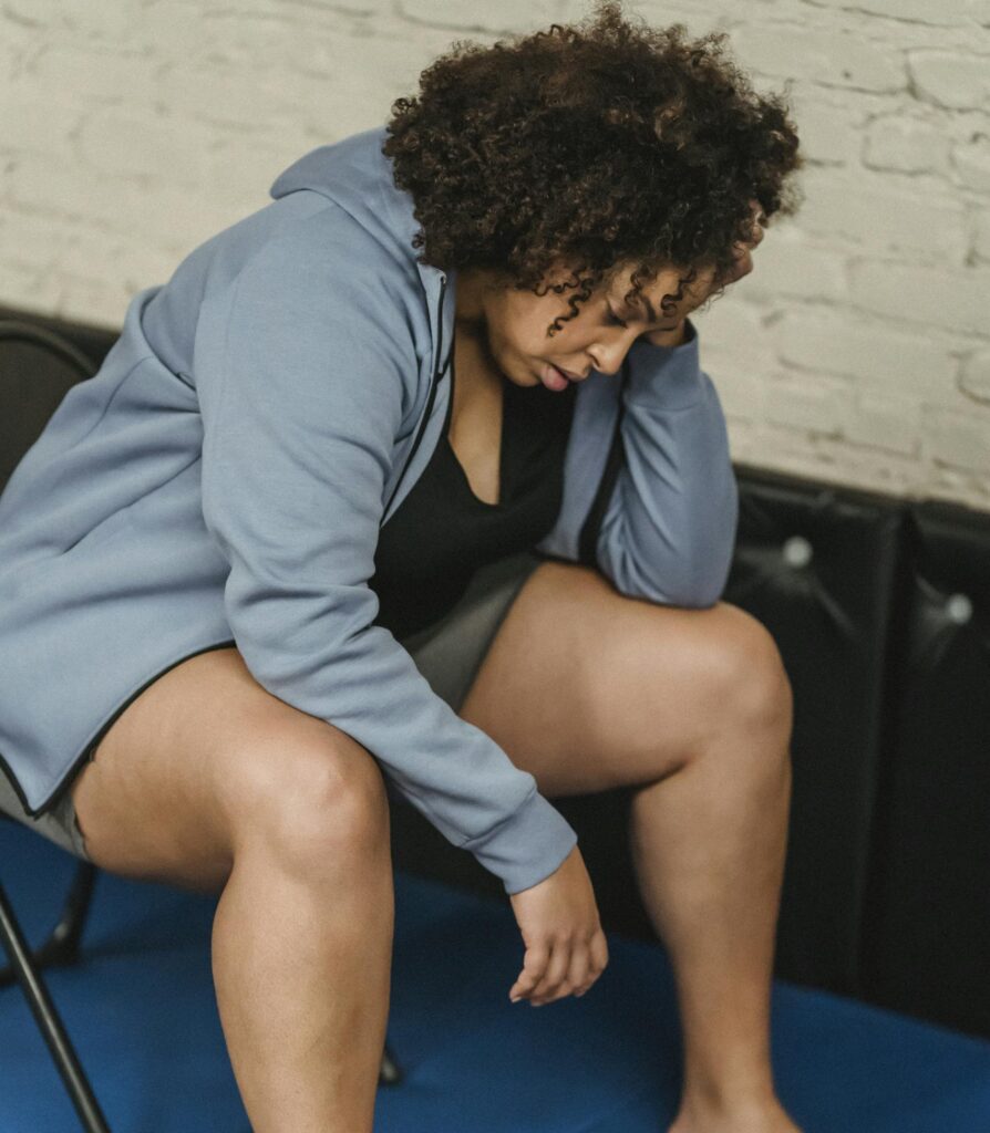 Full body of tired African American female in activewear sitting on chair near boxing gloves during workout in modern gym

plus size burnout signs