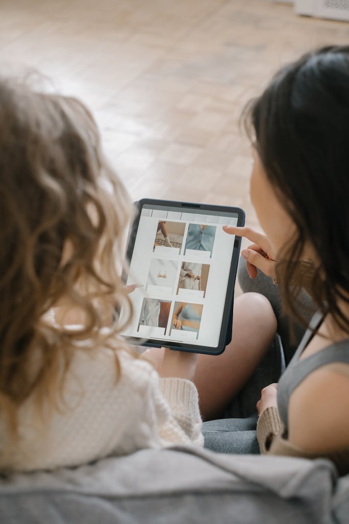 Two women sitting together, shopping online using a tablet, sharing ideas and browsing products  on plus size fashion industry growth