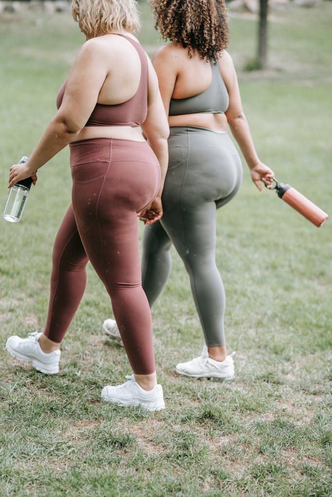 Two women walking on grass in sports clothing, holding water bottles. Focus on fitness and outdoor exercise.

plus size sports bra support