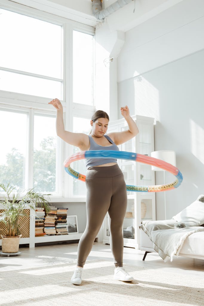Plus size woman hula hooping in a bright indoor space, promoting health and body positivity.