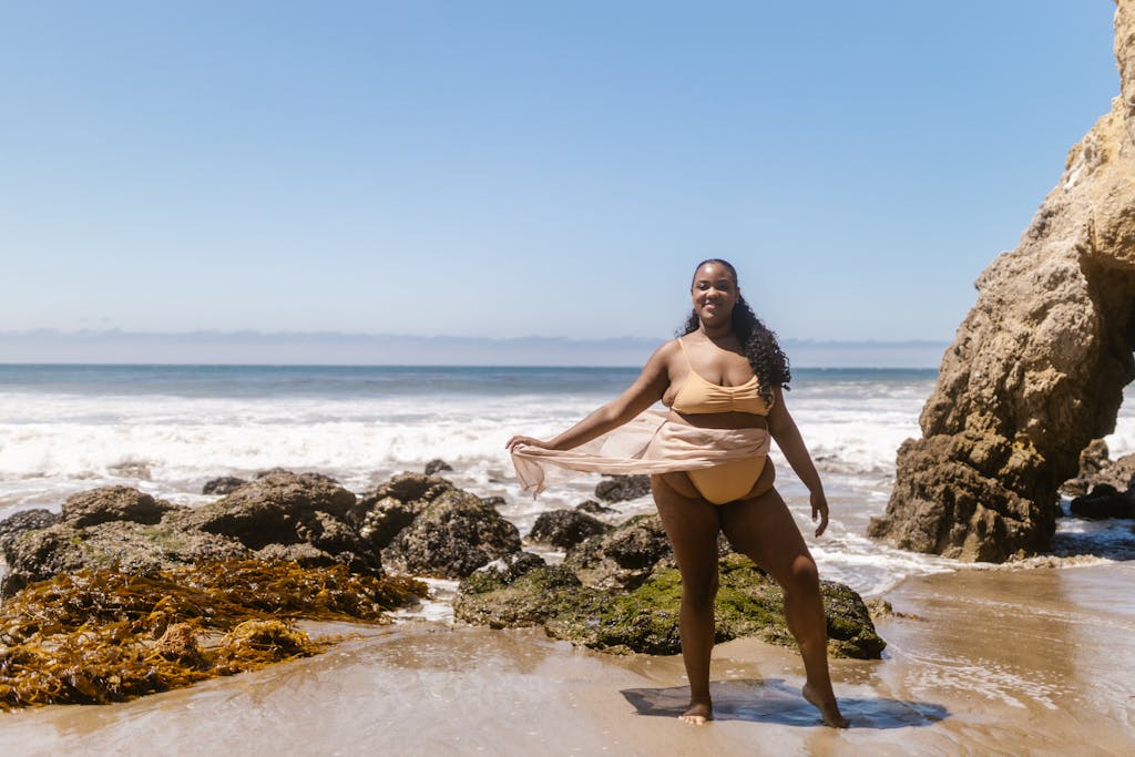 A joyful woman in swimwear poses on a rocky beach under the summer sun.

5 Plus Size Swimsuit Tips That Will Change How You Shop in 2026

