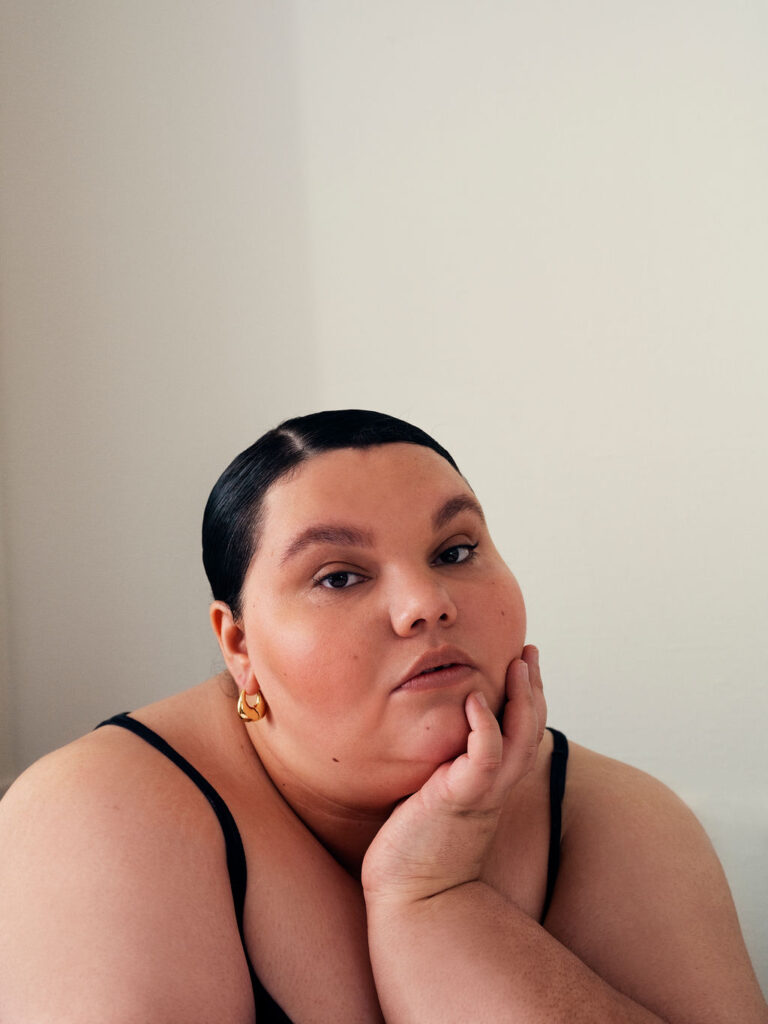 Kartanya Maynard posing during an editorial photoshoot wearing a black outfit with soft lighting..

kartanya maynard plus size representation