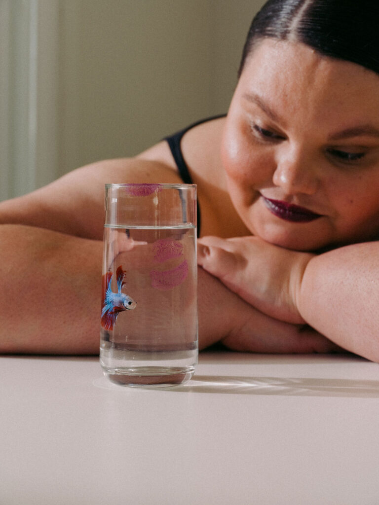 Kartanya Maynard sitting beside a flower and glass during an intimate editorial portrait session.

Kartanya Maynard plus size representation