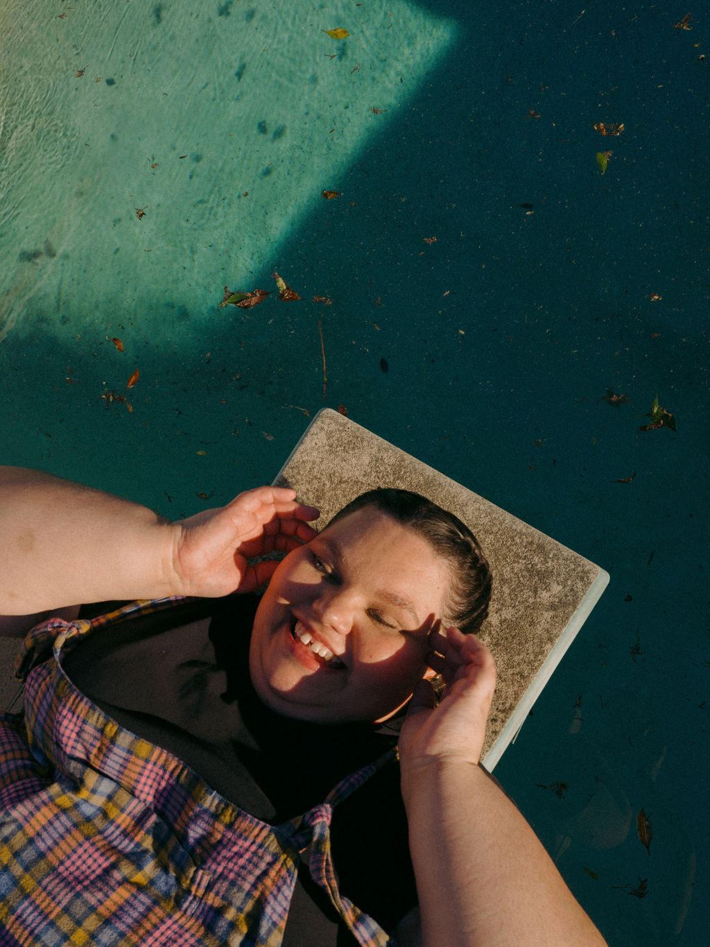 Kartanya Maynard smiling while relaxing beside a swimming pool during an outdoor editorial photoshoot.
Kartanya Maynard plus size representation