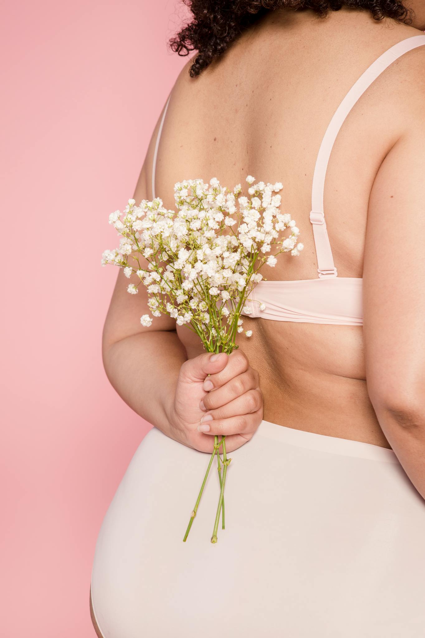 Back view of anonymous plus size female in lingerie standing on pink background with small flowers behind back in light studio

Self-Trust