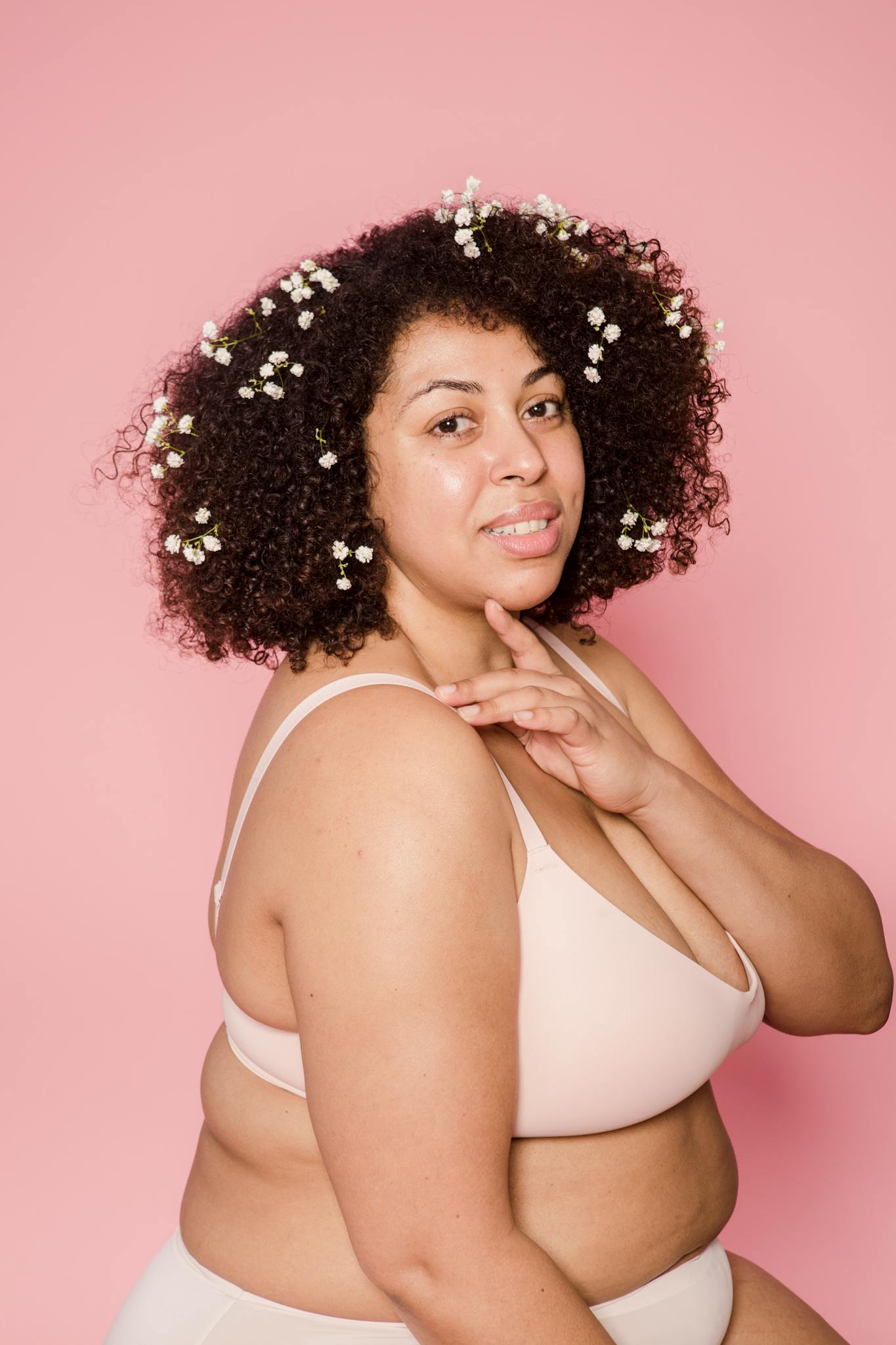 Content plus size African American female model in lingerie and small white flowers in black hair looking at camera on pink background

self-trust