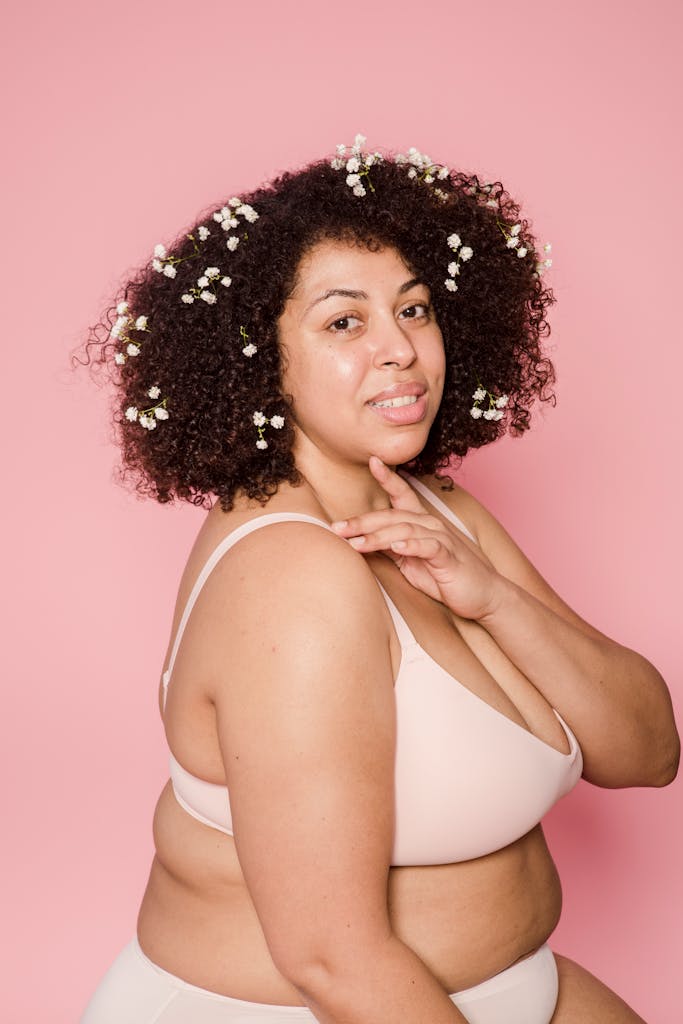 Content plus size African American female model in lingerie and small white flowers in black hair looking at camera on pink background

self-trust