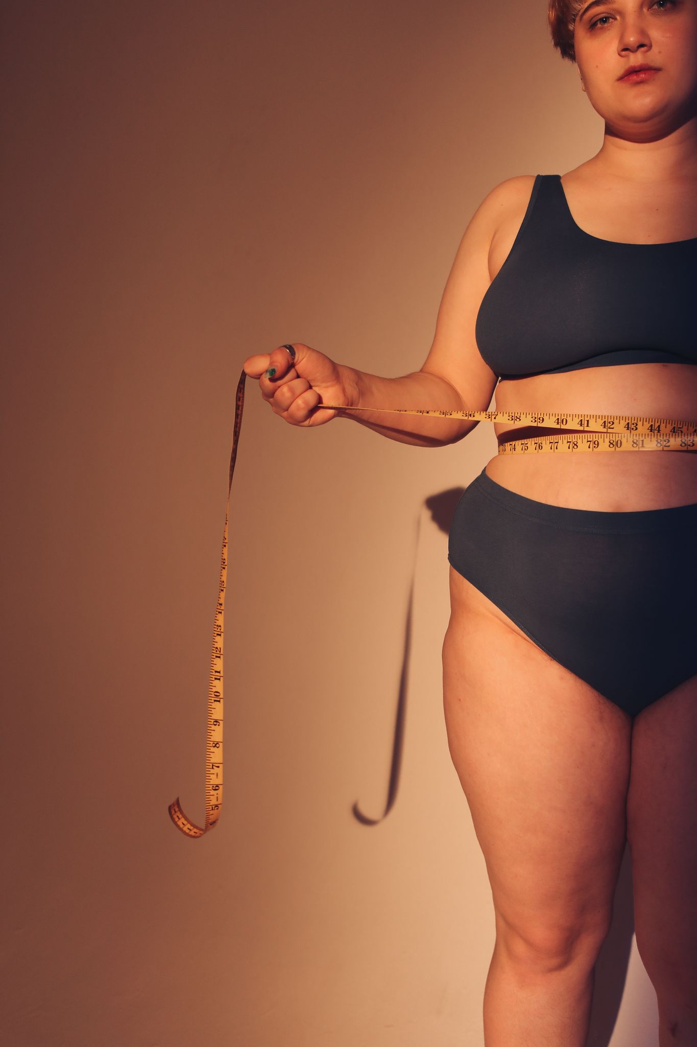 Empowering image of a plus-size woman in underwear embracing body positivity with a measuring tape.
plus size shopping tips