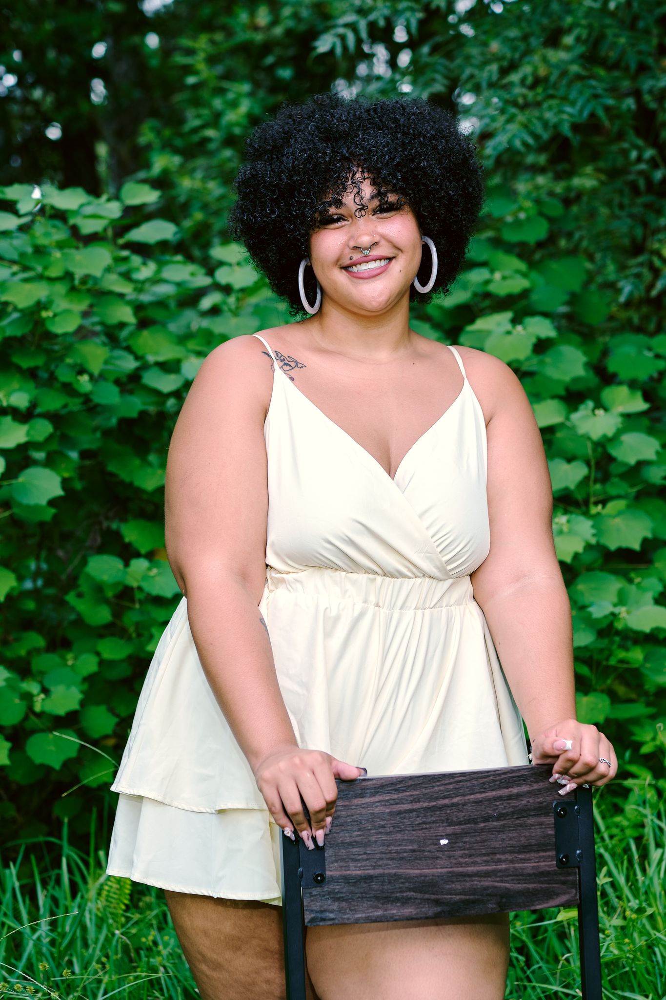 Portrait of a smiling woman outdoors in a summer dress holding a chair.