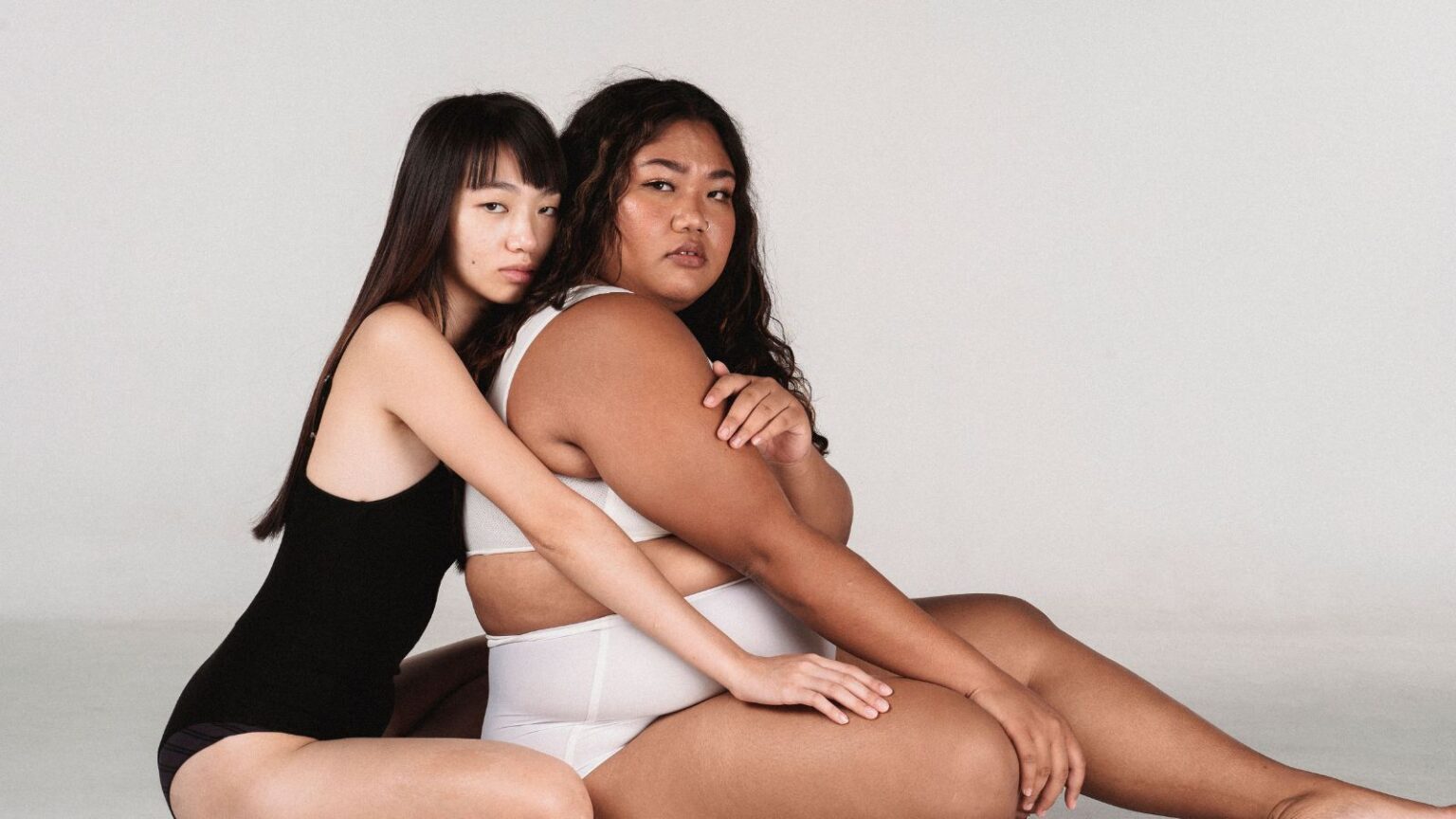 Studio portrait of two women embracing showcasing diversity