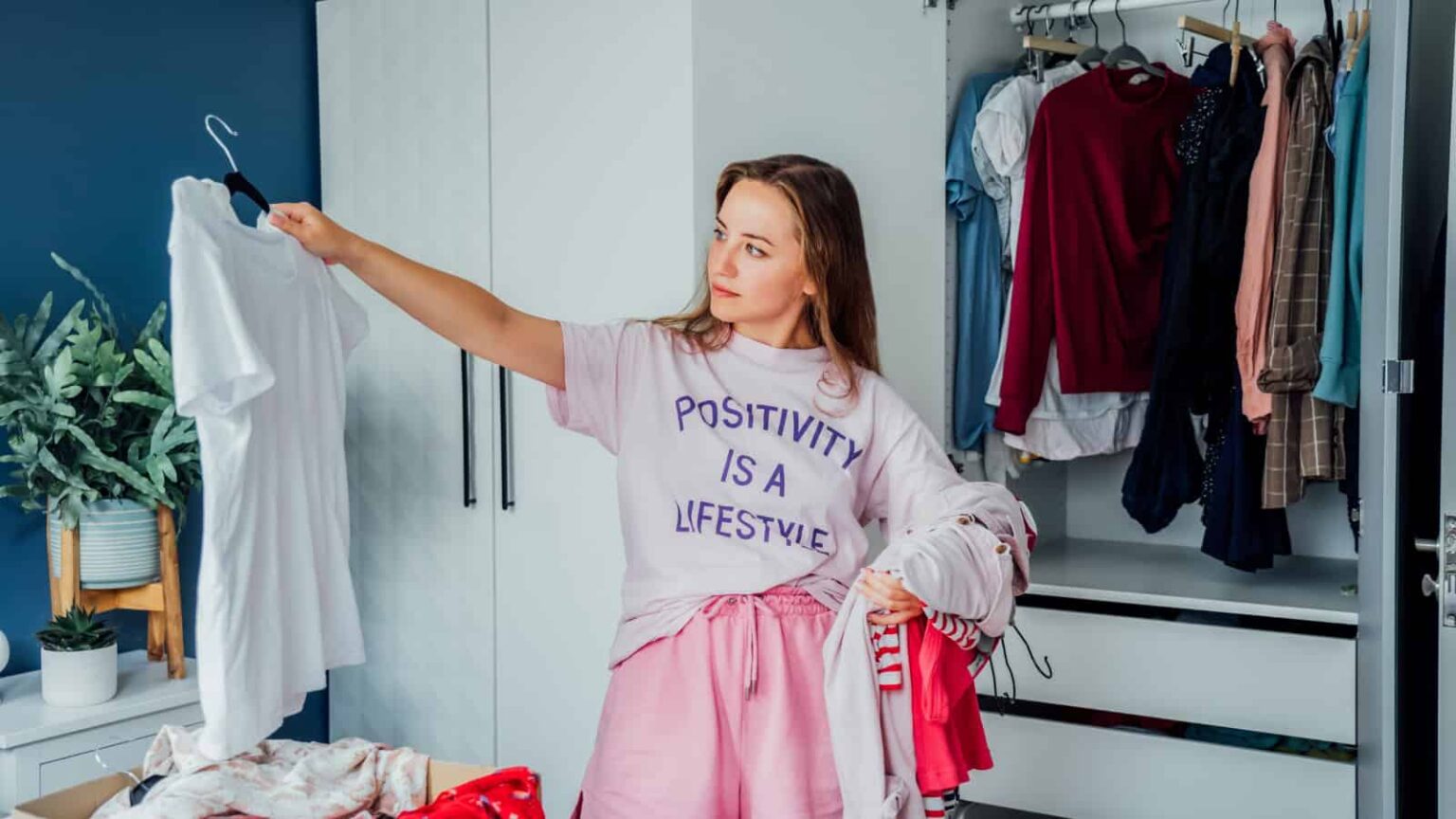 Woman selecting clothes from her wardrobe for donating to a Charity shop. Decluttering Sorting clothes and Cleaning Up. Reuse second hand concept. Conscious consumer sustainable lifestyle