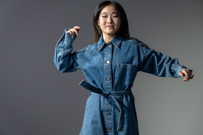 A fashionable woman poses confidently in a denim dress, showcasing modern style.