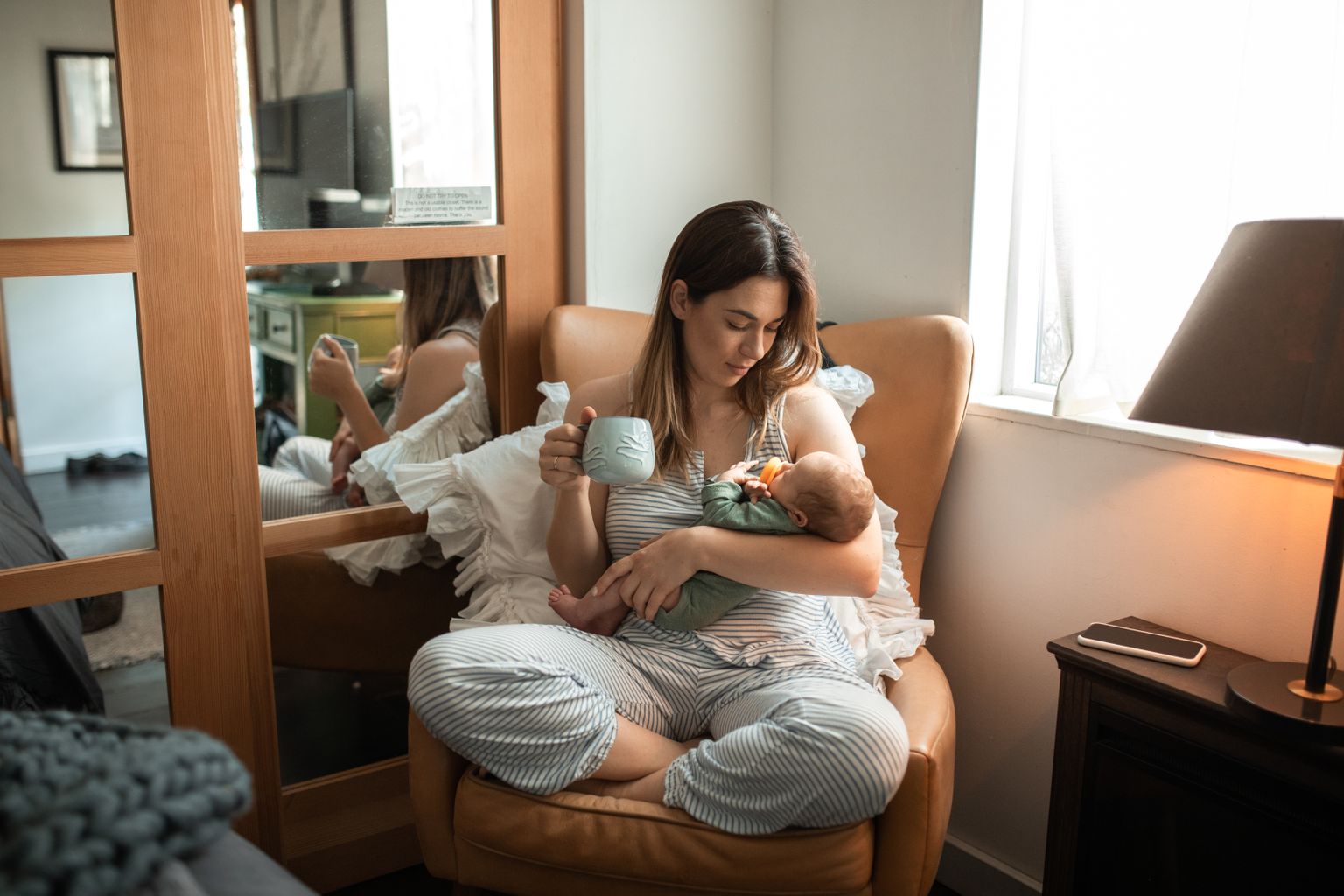 Mother cradling newborn in a cozy indoor setup. Perfect family and lifestyle theme.