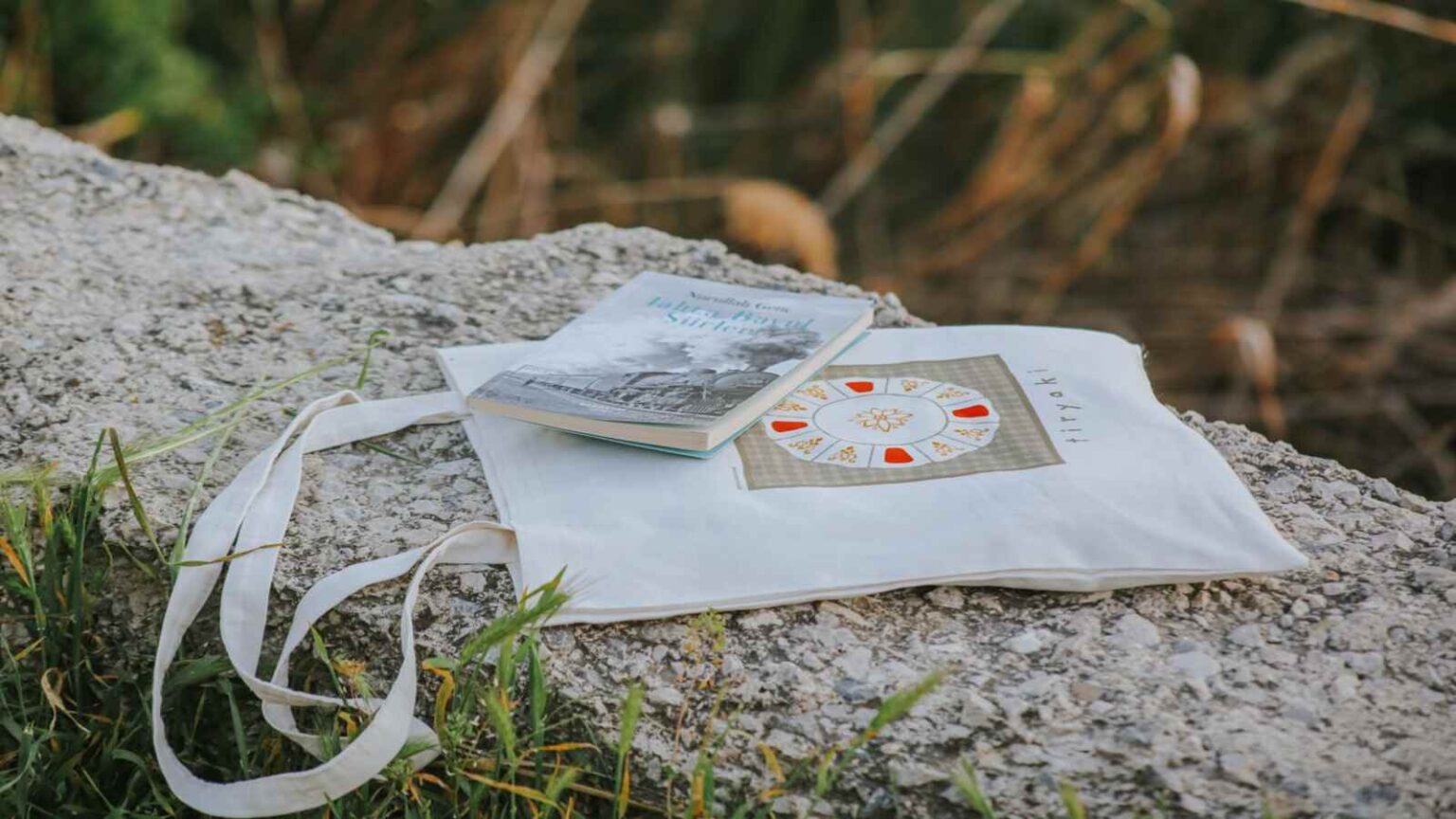 photobook and tote bag on a stone surface outdoors 34800392