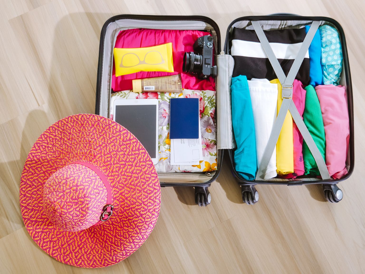 top view of a suitcase packed with clothes a camera and a sun hat ready for summer travel. 8212231