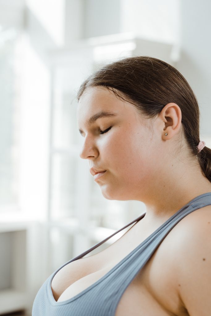 Plus size woman meditating indoors, embracing body positivity and mindfulness.
