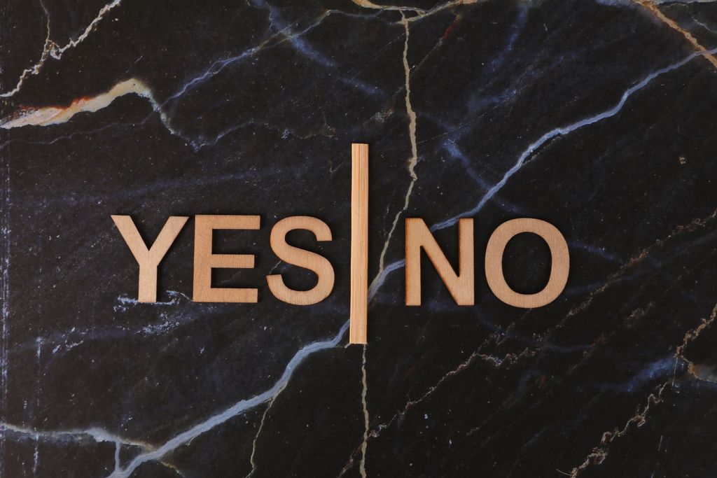 A stylish contrast of wooden letters 'Yes' and 'No' on dark marble background.
