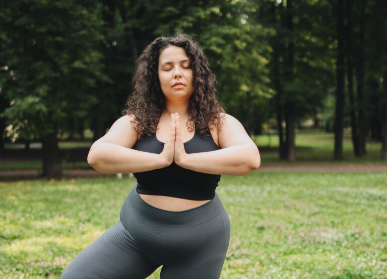 Confident plus size woman practicing yoga outdoors on a sunny day.